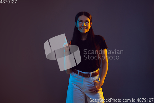Image of Caucasian young woman\'s portrait on dark background in neon light