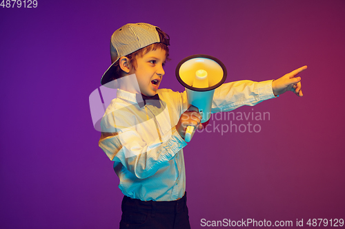 Image of Caucasian boy\'s portrait on gradient studio background in neon light. Beautiful curly model. Concept of human emotions, facial expression, sales, ad, tech