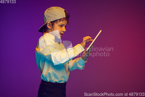 Image of Caucasian boy\'s portrait on gradient studio background in neon light. Beautiful curly model. Concept of human emotions, facial expression, sales, ad, tech