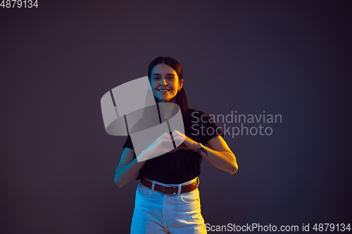 Image of Caucasian young woman\'s portrait on dark background in neon light