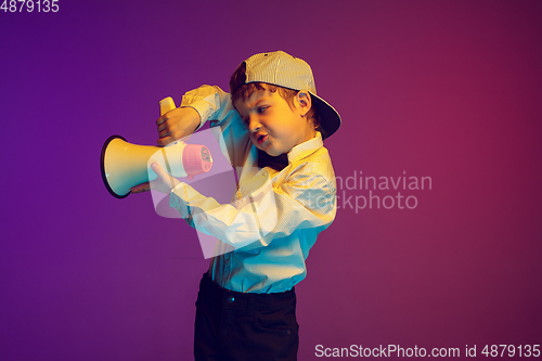 Image of Caucasian boy\'s portrait on gradient studio background in neon light. Beautiful curly model. Concept of human emotions, facial expression, sales, ad, tech