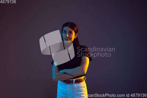 Image of Caucasian young woman\'s portrait on dark background in neon light