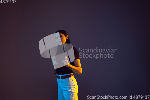 Image of Caucasian young woman\'s portrait on dark background in neon light