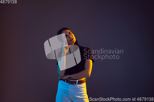 Image of Caucasian young woman\'s portrait on dark background in neon light