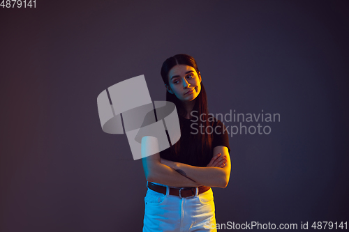 Image of Caucasian young woman\'s portrait on dark background in neon light