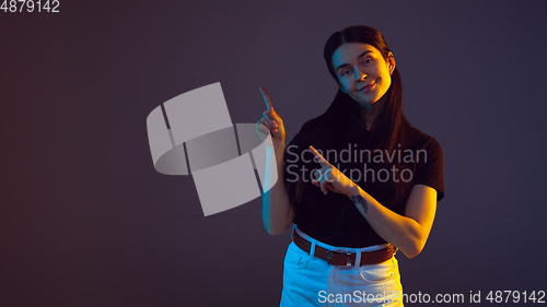 Image of Caucasian young woman\'s portrait on dark background in neon light