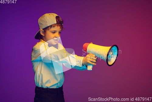 Image of Caucasian boy\'s portrait on gradient studio background in neon light. Beautiful curly model. Concept of human emotions, facial expression, sales, ad, tech