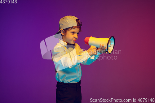 Image of Caucasian boy\'s portrait on gradient studio background in neon light. Beautiful curly model. Concept of human emotions, facial expression, sales, ad, tech