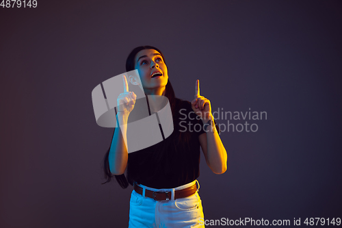 Image of Caucasian young woman\'s portrait on dark background in neon light