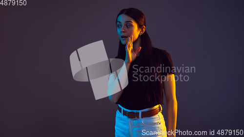 Image of Caucasian young woman\'s portrait on dark background in neon light