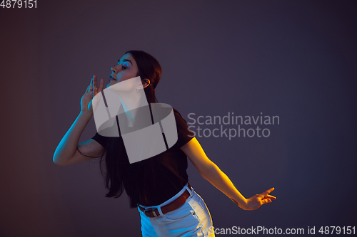 Image of Caucasian young woman\'s portrait on dark background in neon light