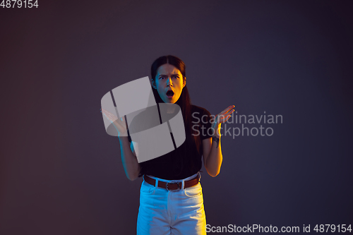 Image of Caucasian young woman\'s portrait on dark background in neon light