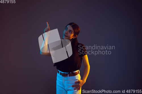 Image of Caucasian young woman\'s portrait on dark background in neon light