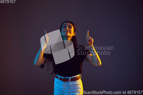 Image of Caucasian young woman\'s portrait on dark background in neon light