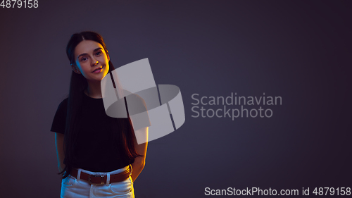 Image of Caucasian young woman\'s portrait on dark background in neon light