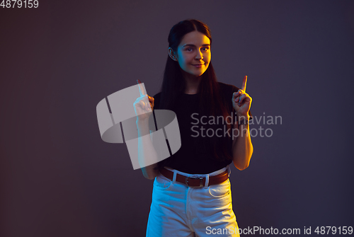 Image of Caucasian young woman\'s portrait on dark background in neon light
