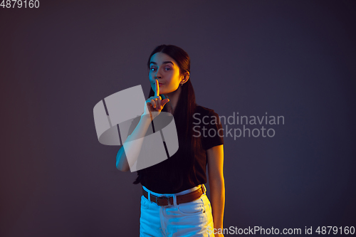 Image of Caucasian young woman\'s portrait on dark background in neon light