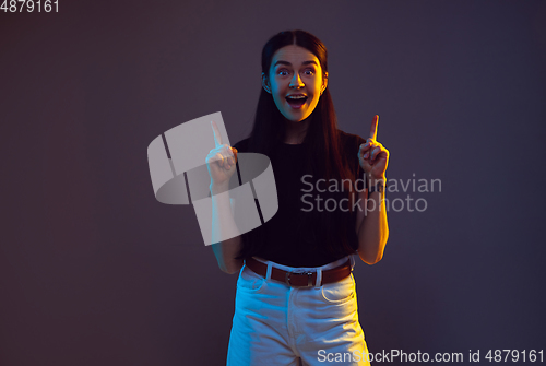 Image of Caucasian young woman\'s portrait on dark background in neon light