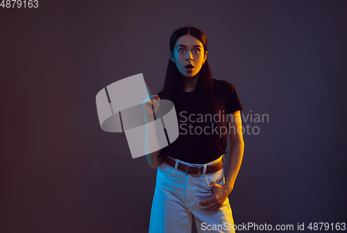 Image of Caucasian young woman\'s portrait on dark background in neon light