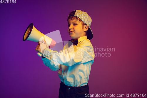 Image of Caucasian boy\'s portrait on gradient studio background in neon light. Beautiful curly model. Concept of human emotions, facial expression, sales, ad, tech