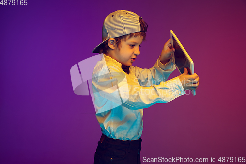 Image of Caucasian boy\'s portrait on gradient studio background in neon light. Beautiful curly model. Concept of human emotions, facial expression, sales, ad, tech