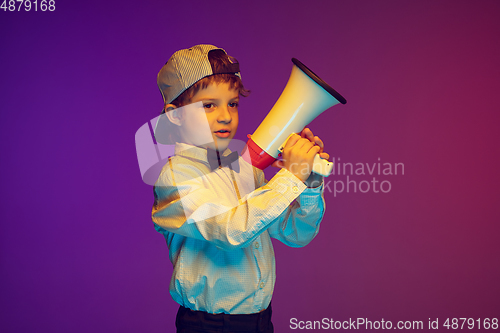 Image of Caucasian boy\'s portrait on gradient studio background in neon light. Beautiful curly model. Concept of human emotions, facial expression, sales, ad, tech