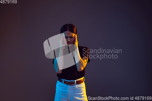 Image of Caucasian young woman\'s portrait on dark background in neon light