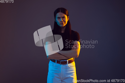 Image of Caucasian young woman\'s portrait on dark background in neon light