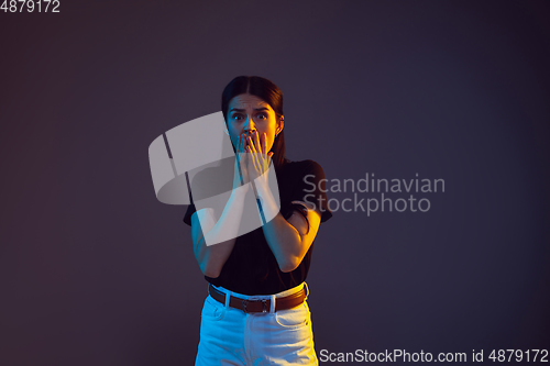 Image of Caucasian young woman\'s portrait on dark background in neon light