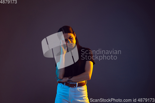 Image of Caucasian young woman\'s portrait on dark background in neon light