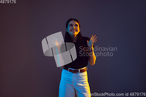Image of Caucasian young woman\'s portrait on dark background in neon light