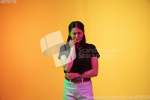Image of Caucasian young woman\'s portrait on yellow background in neon light