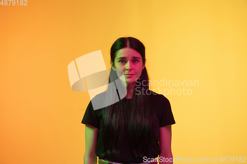 Image of Caucasian young woman\'s portrait on yellow background in neon light