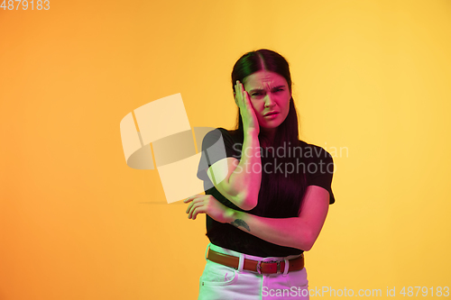 Image of Caucasian young woman\'s portrait on yellow background in neon light