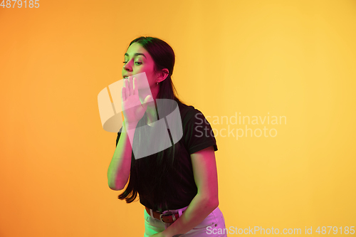 Image of Caucasian young woman\'s portrait on yellow background in neon light