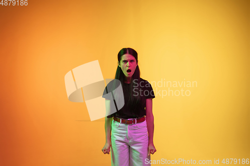 Image of Caucasian young woman\'s portrait on yellow background in neon light