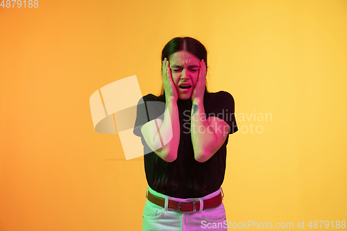 Image of Caucasian young woman\'s portrait on yellow background in neon light