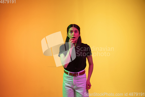 Image of Caucasian young woman\'s portrait on yellow background in neon light