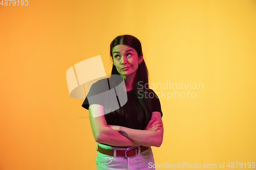 Image of Caucasian young woman\'s portrait on yellow background in neon light