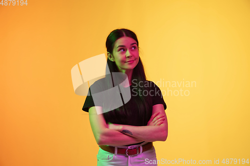 Image of Caucasian young woman\'s portrait on yellow background in neon light