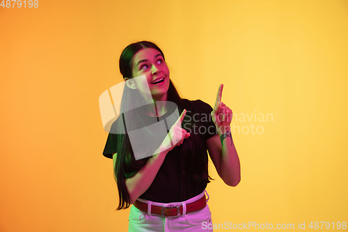Image of Caucasian young woman\'s portrait on yellow background in neon light