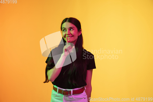 Image of Caucasian young woman\'s portrait on yellow background in neon light