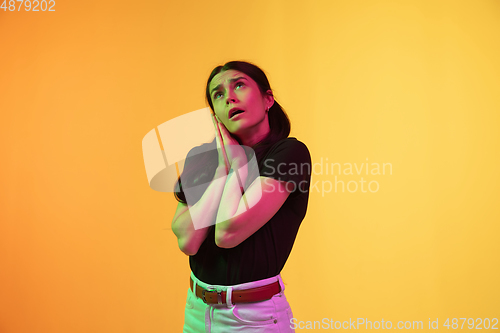 Image of Caucasian young woman\'s portrait on yellow background in neon light