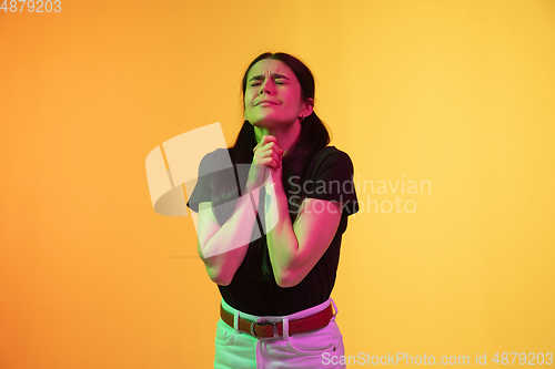 Image of Caucasian young woman\'s portrait on yellow background in neon light