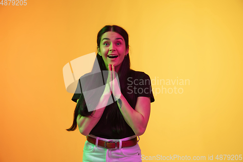 Image of Caucasian young woman\'s portrait on yellow background in neon light