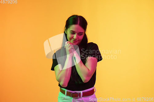 Image of Caucasian young woman\'s portrait on yellow background in neon light