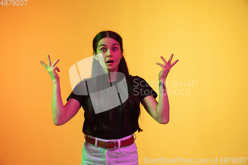 Image of Caucasian young woman\'s portrait on yellow background in neon light