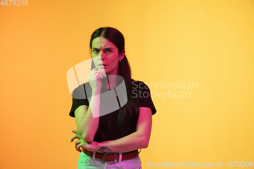 Image of Caucasian young woman\'s portrait on yellow background in neon light