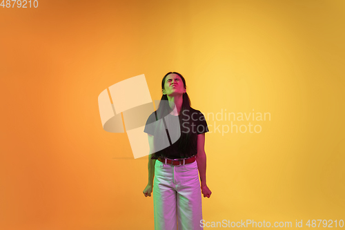 Image of Caucasian young woman\'s portrait on yellow background in neon light