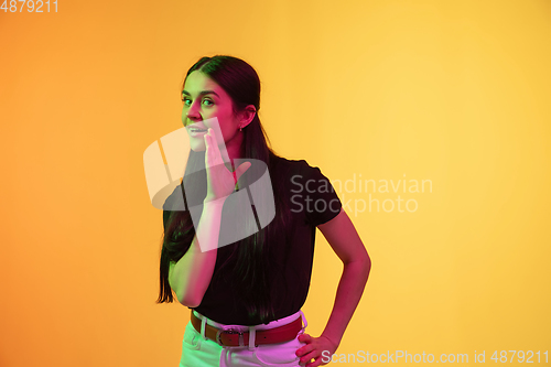 Image of Caucasian young woman\'s portrait on yellow background in neon light
